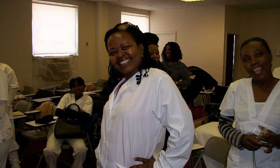 A woman in a white shirt is smiling in a room with other people