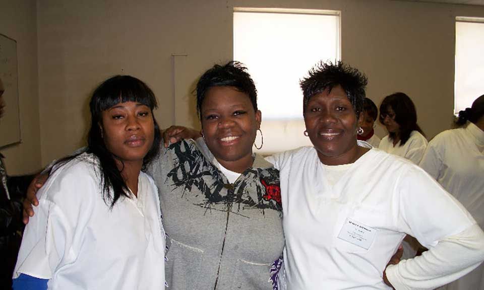 Three women posing for a picture with one wearing a name tag