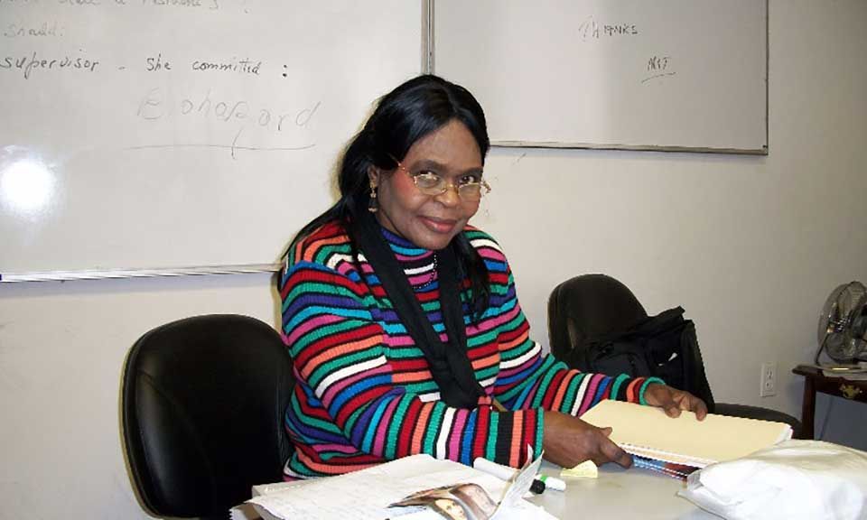 A woman in a striped sweater sits at a desk