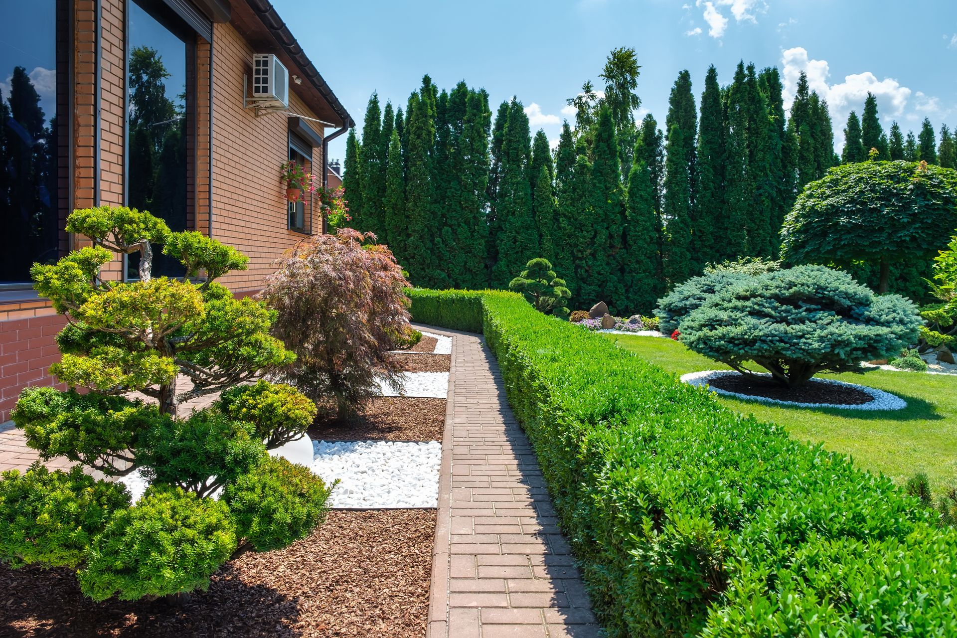 A brick house with a lush green garden in front of it.