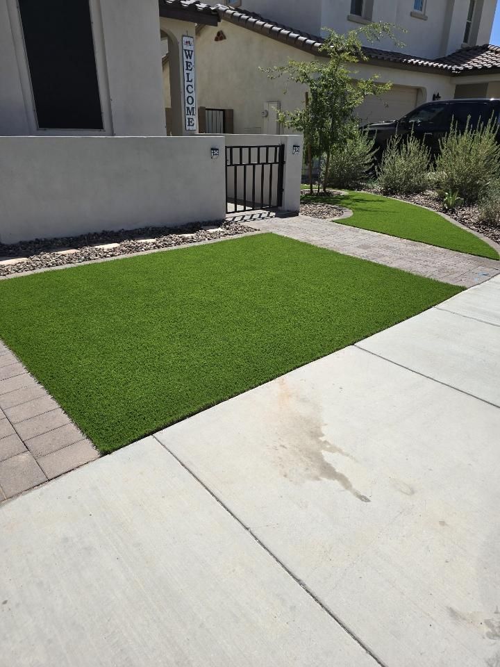 A driveway with a large patch of green grass in front of a house.