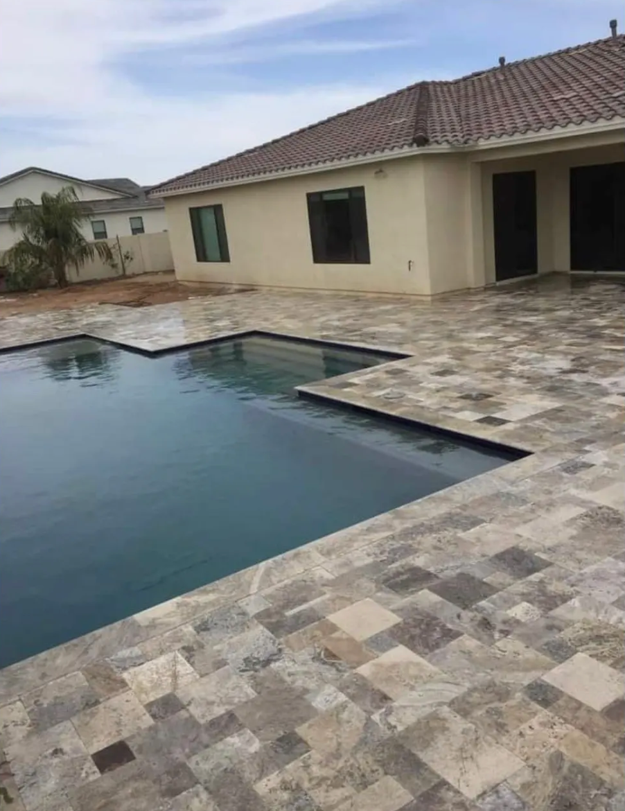 A large swimming pool is in the backyard of a house.