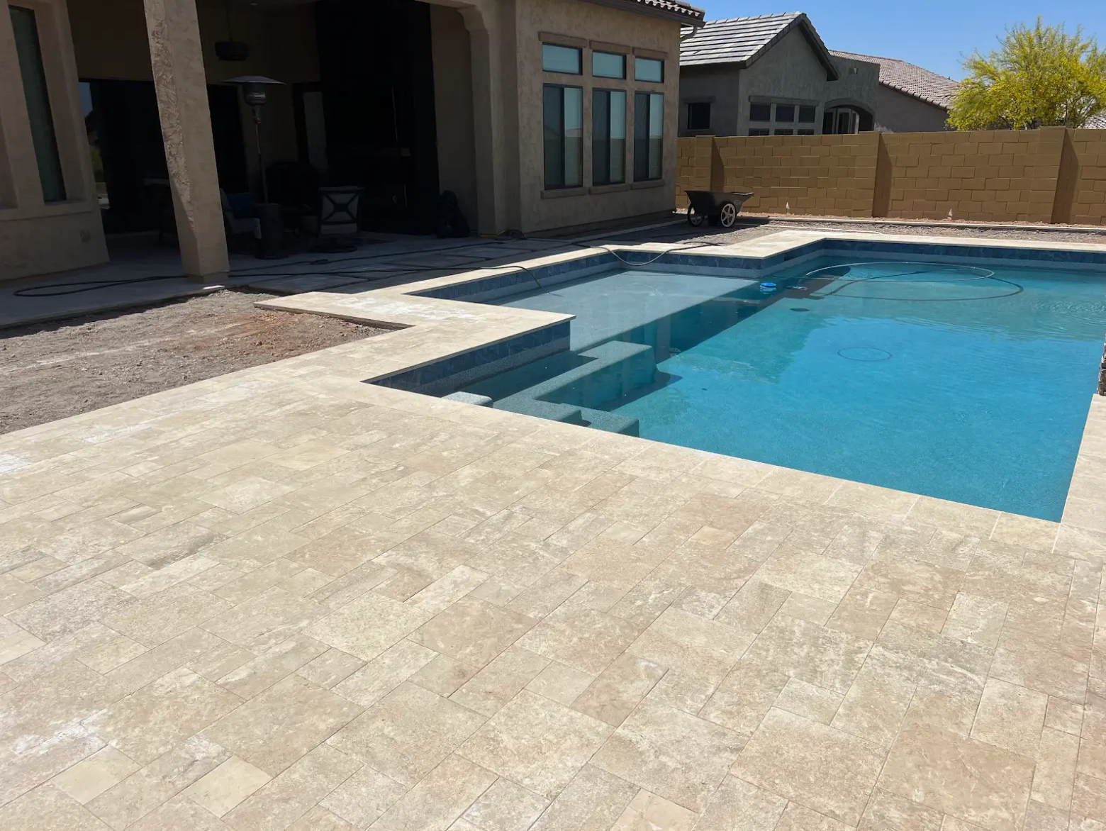 A large swimming pool is in the backyard of a house.