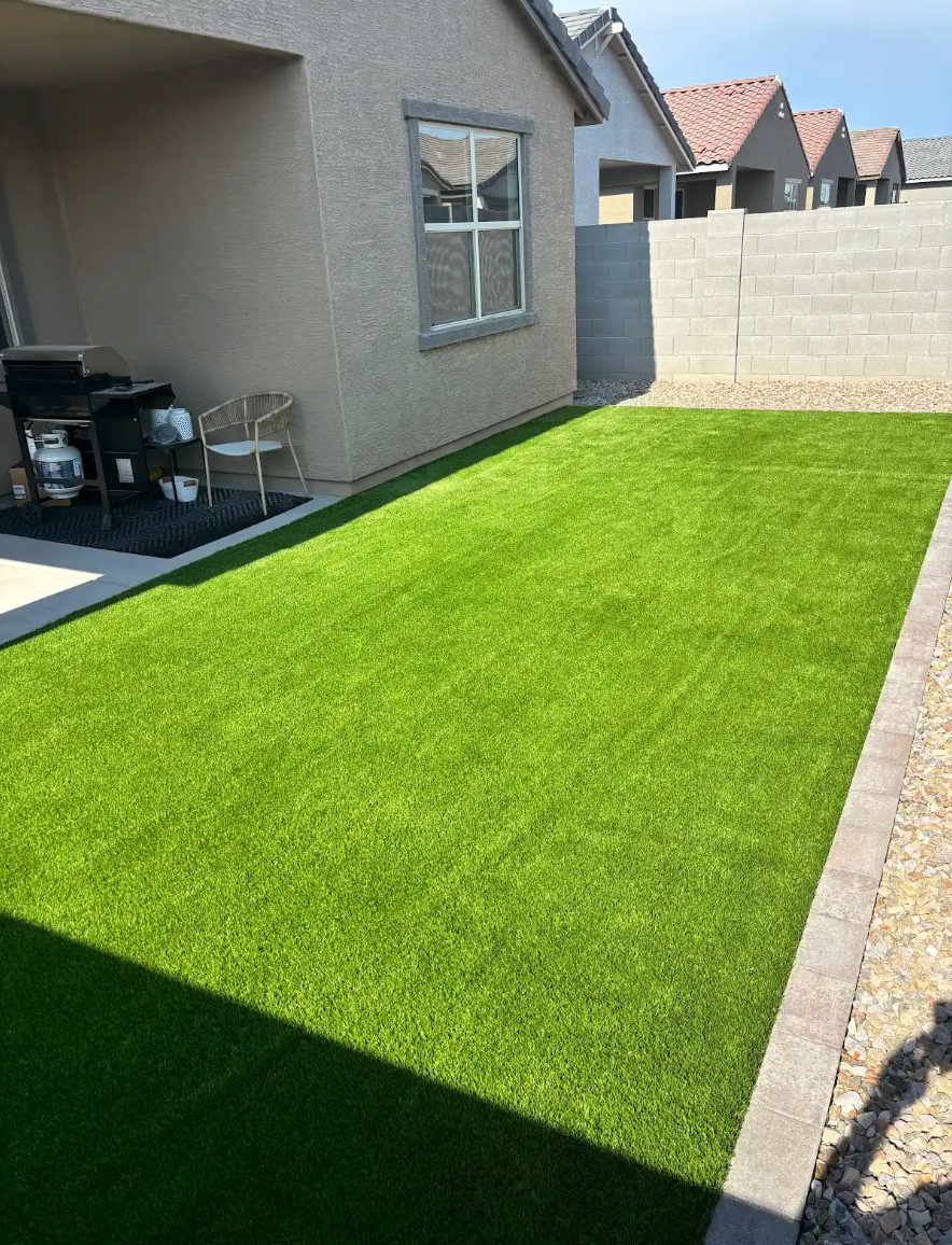 A backyard with a lot of green grass and a house in the background.