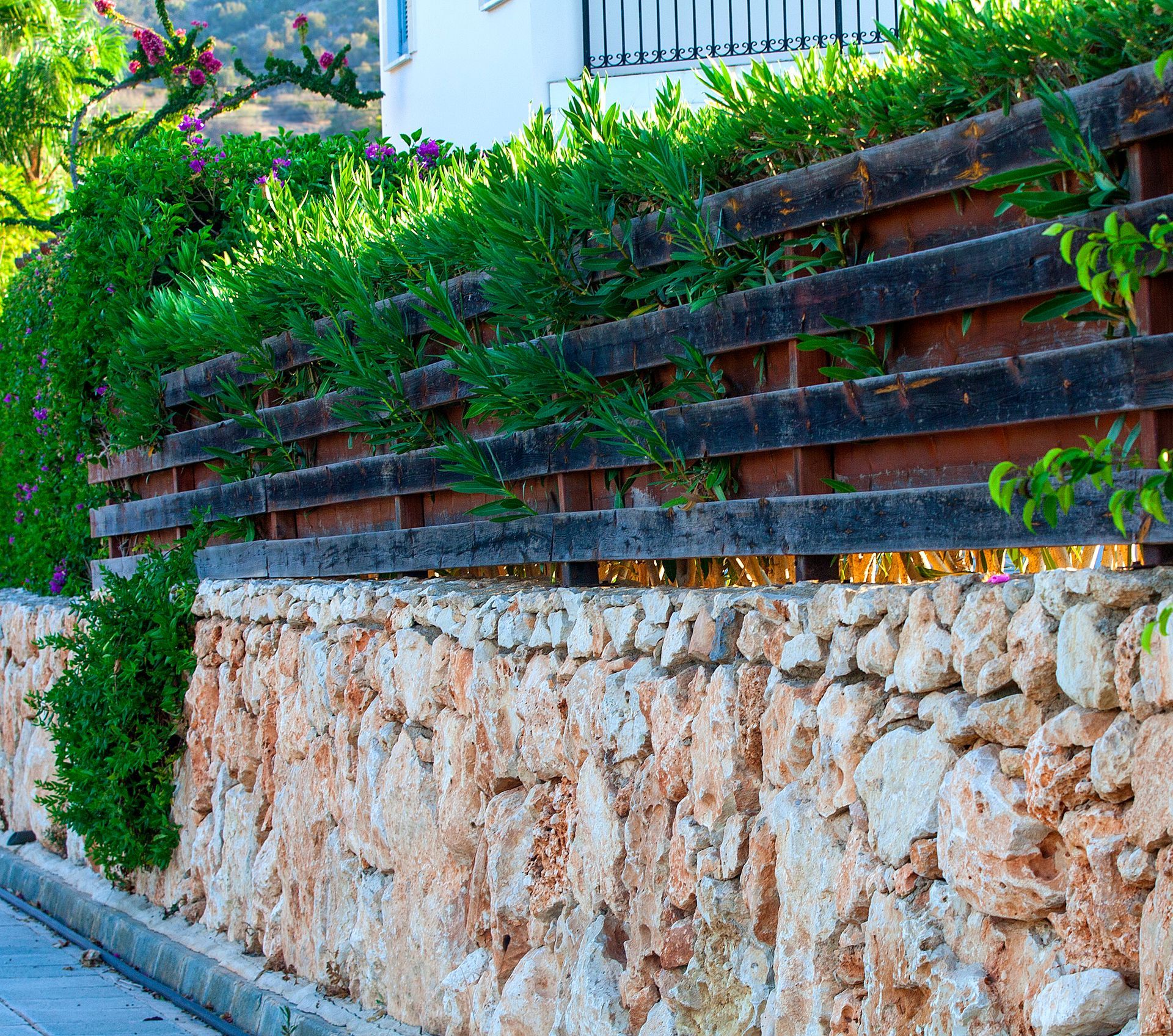 A stone wall with a wooden fence surrounding it