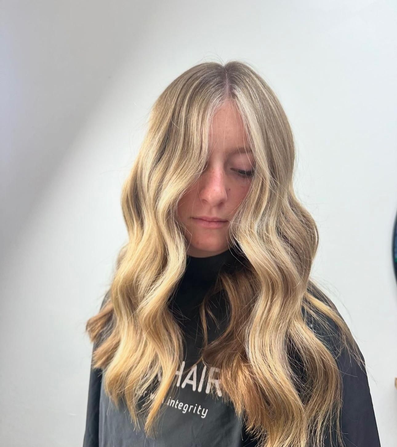 A Woman With Long Blonde Hair Is Wearing A Black Cape — Freedom Hairdressing In Casino, NSW