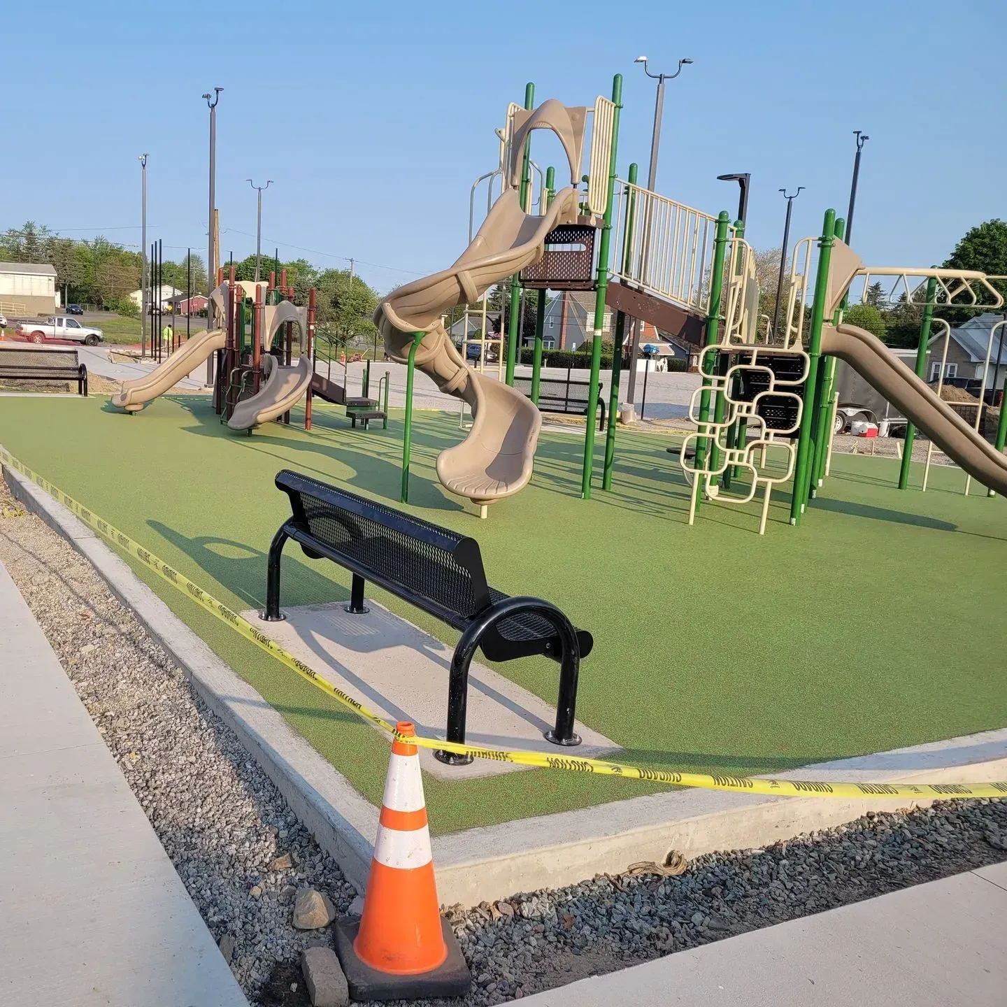A playground with a bench and a cone on the sidewalk