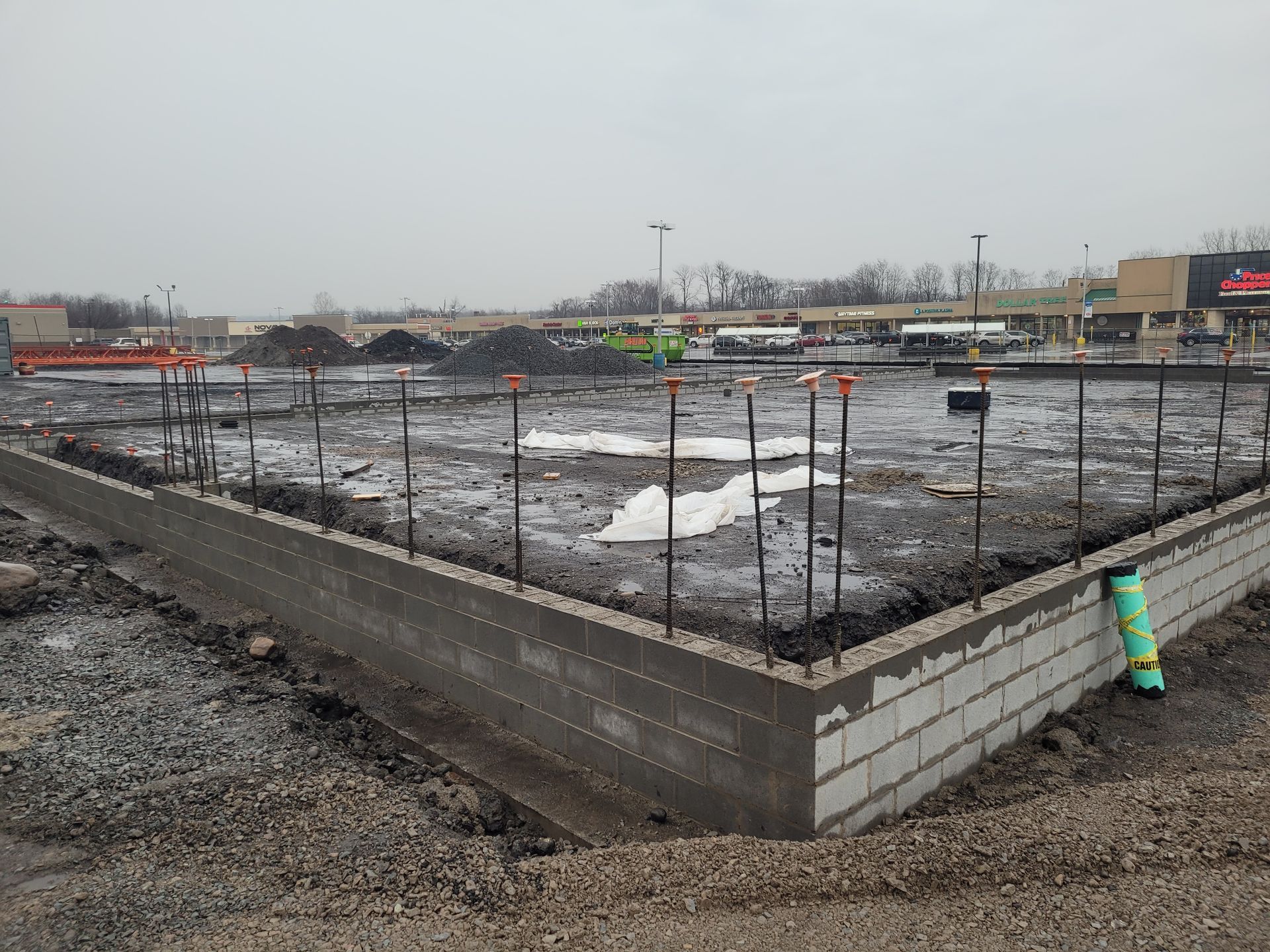 A construction site with a fence around it and a building in the background.