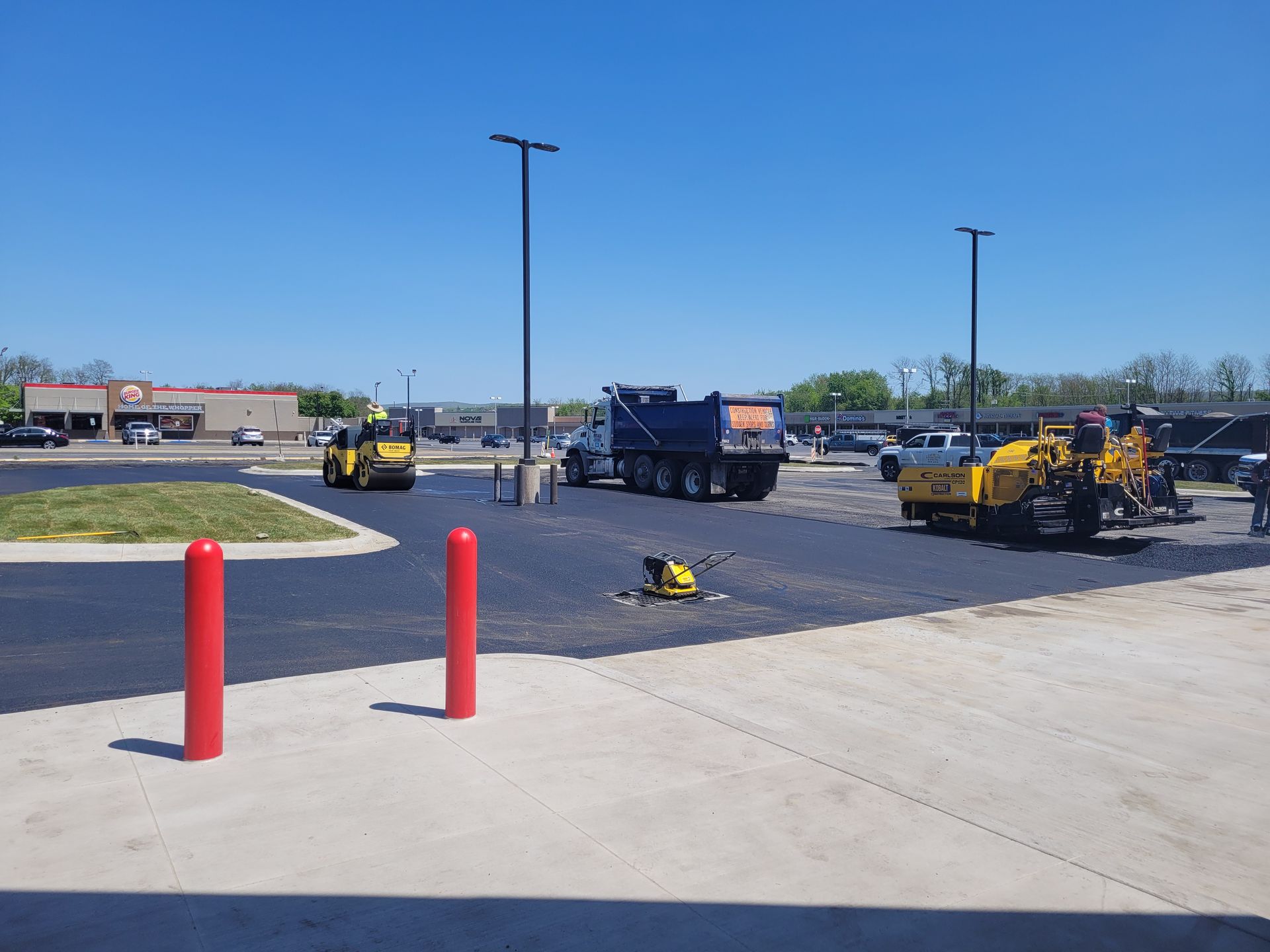 A dump truck is being loaded with asphalt in a parking lot.