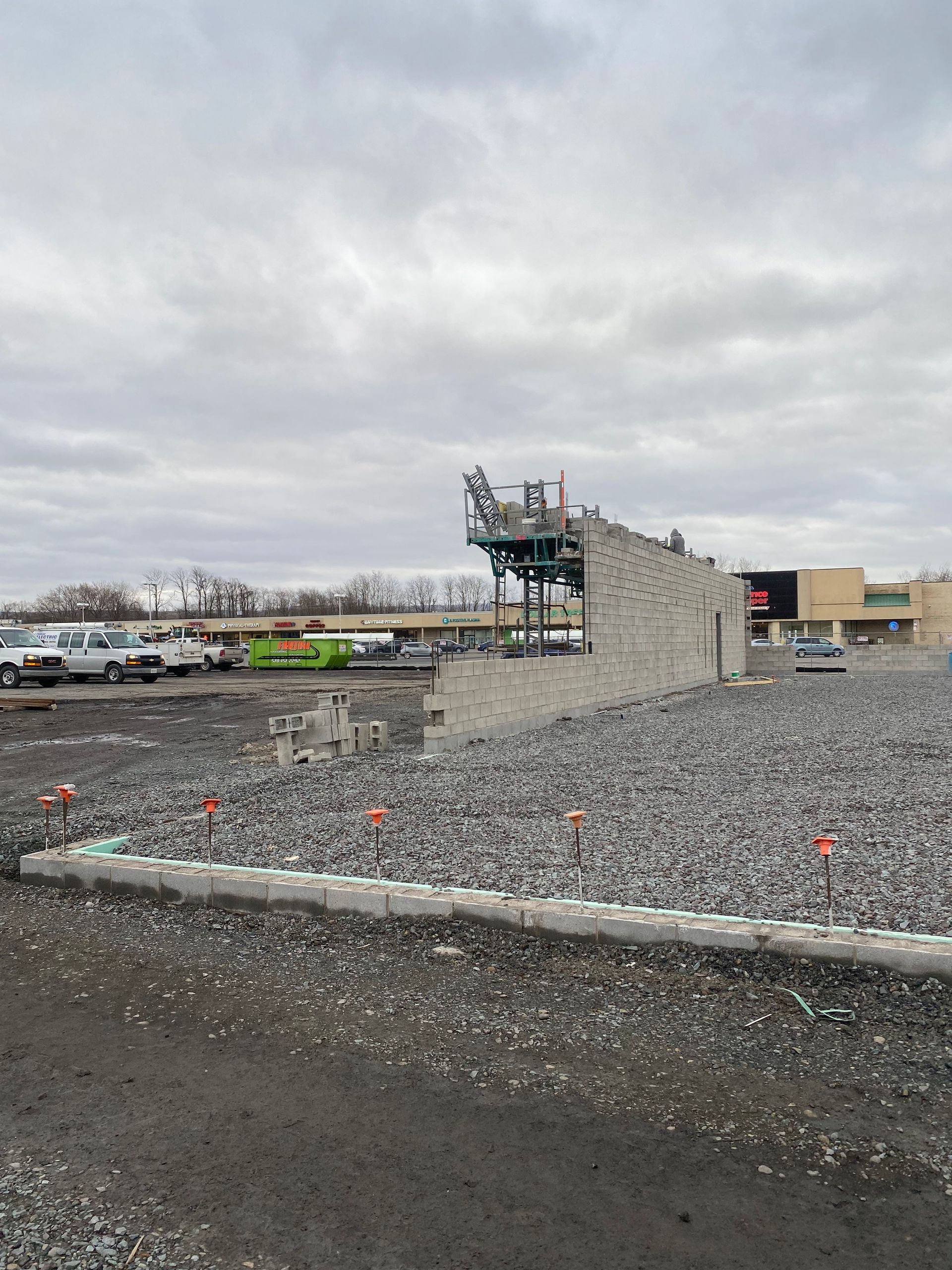 A large concrete structure is being built in a gravel lot.