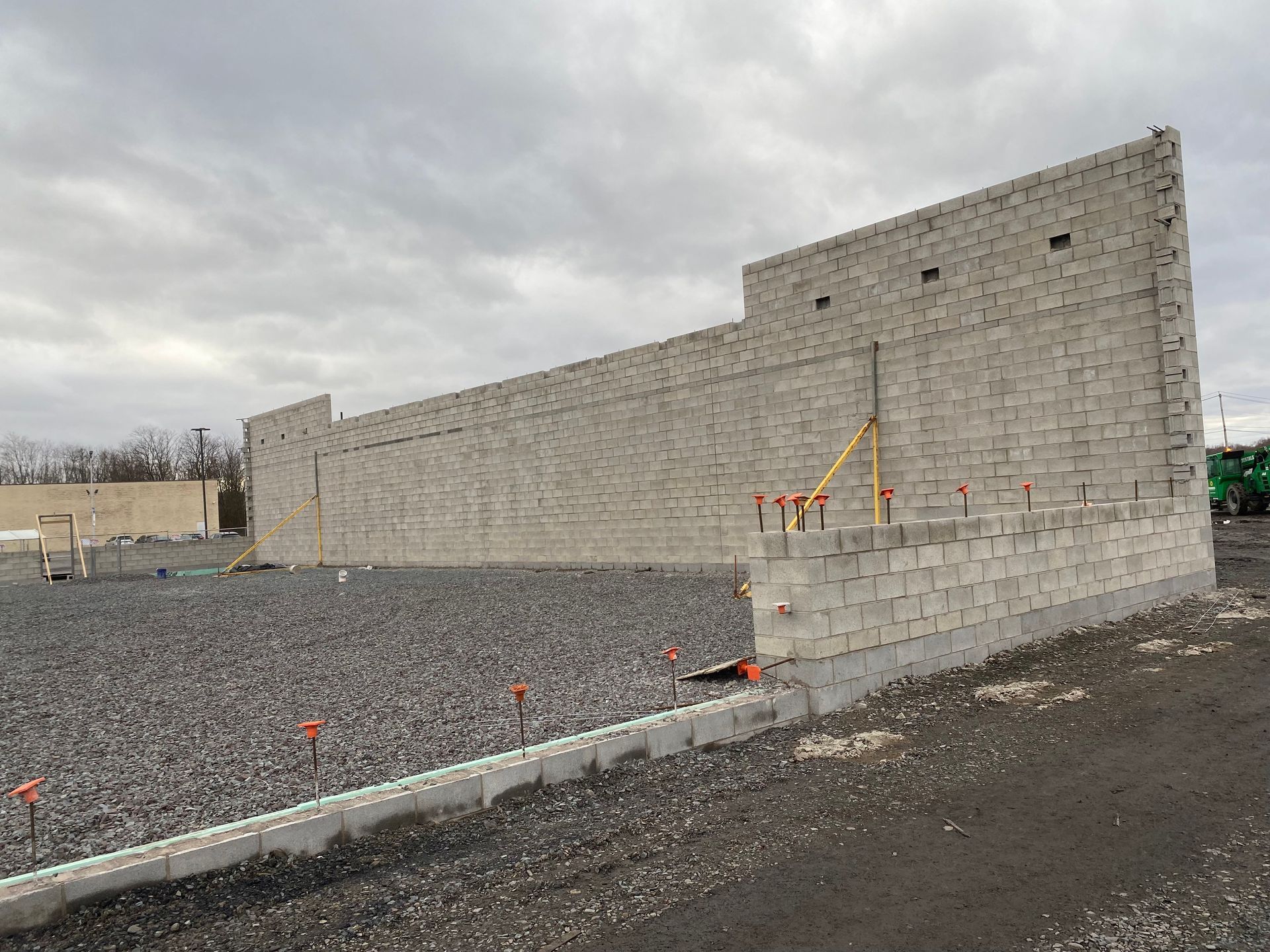 A large brick wall is being built in a gravel area.