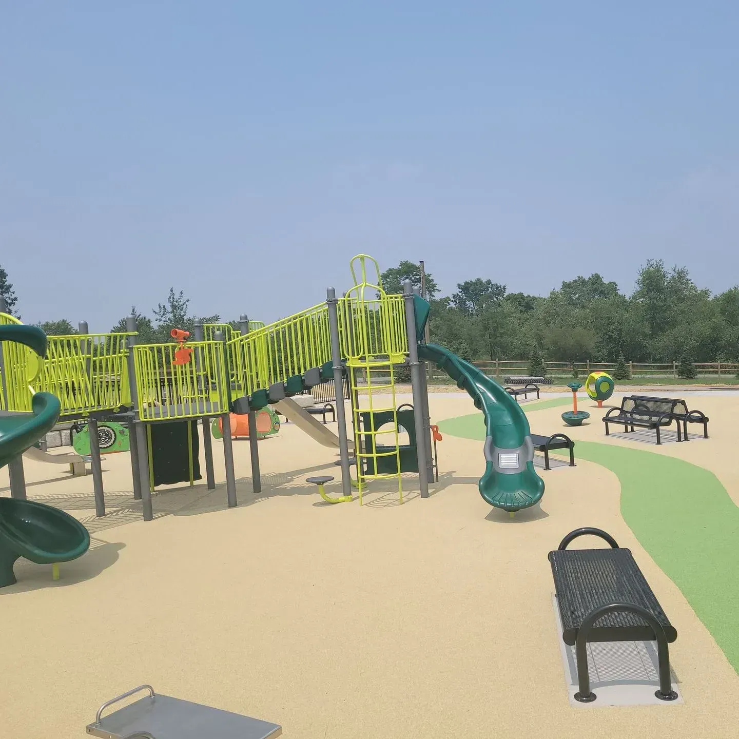 A playground with a green slide and a bench