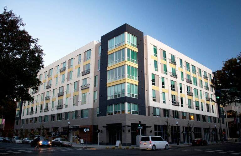 A large building with a lot of windows is on the corner of a street.