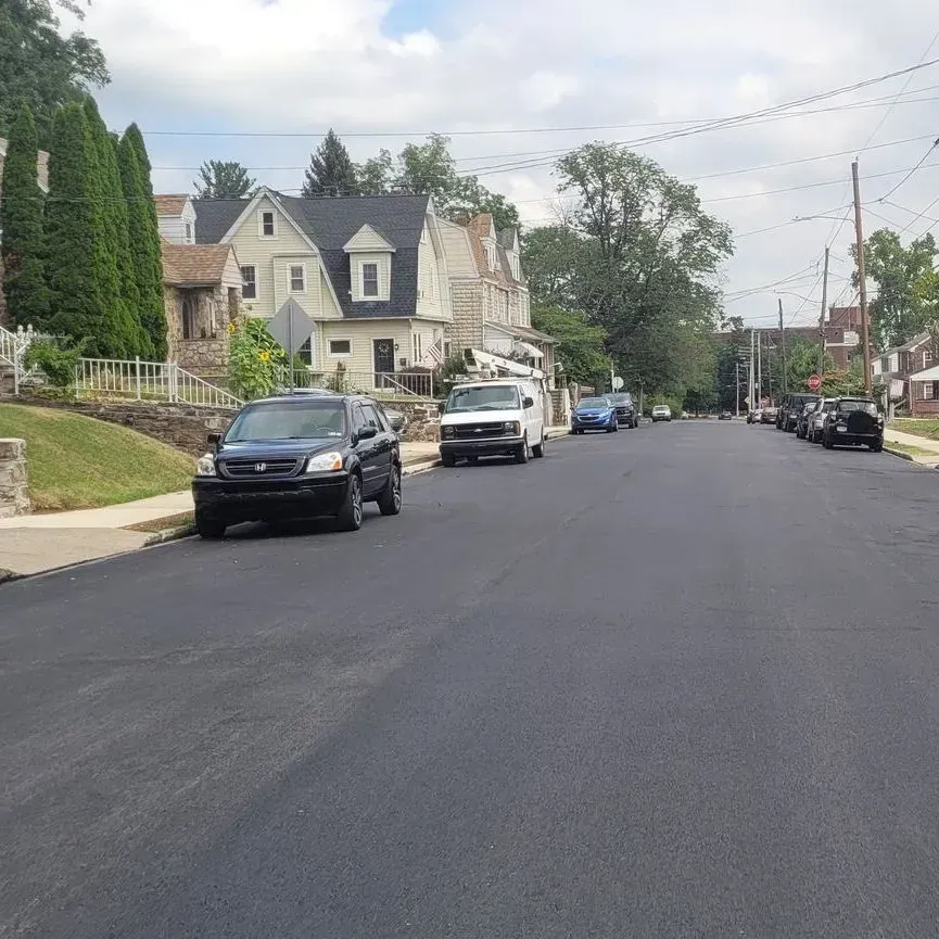 A row of cars are parked on the side of a street