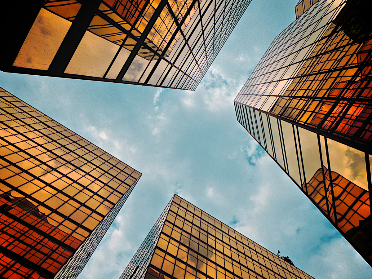 Looking up at a group of tall buildings with a blue sky in the background.