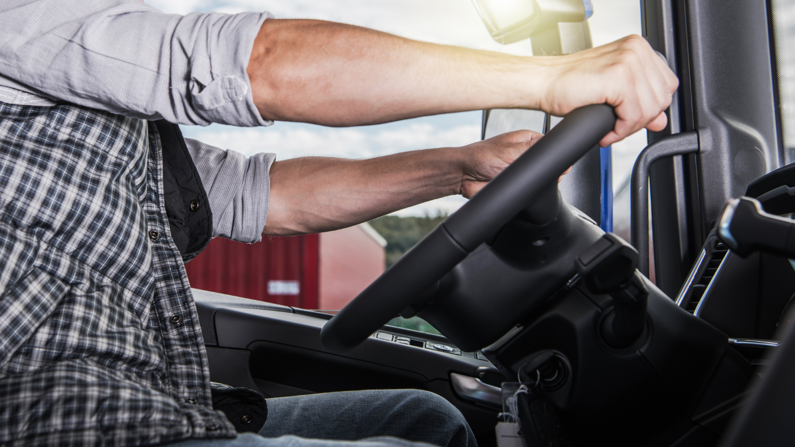 A man is driving a truck with his hands on the steering wheel.