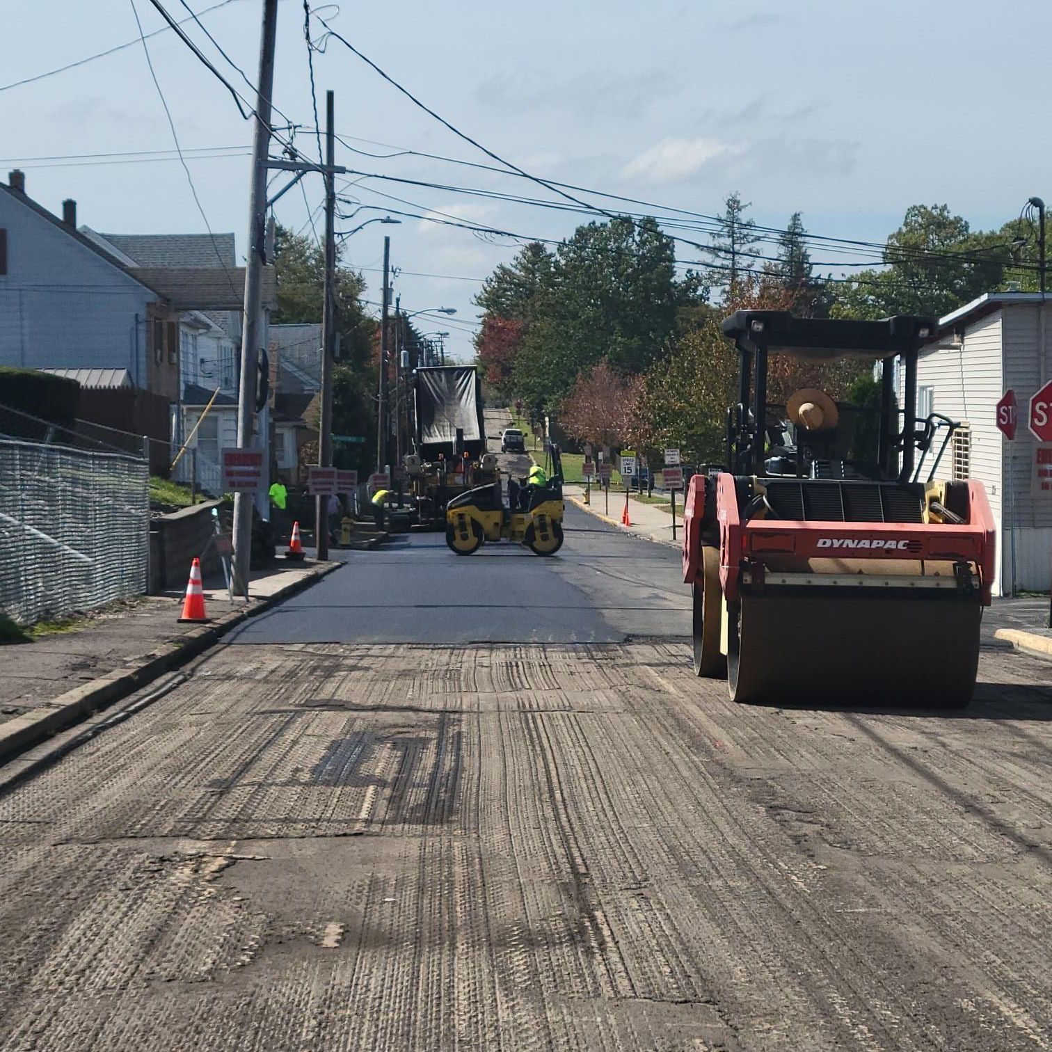 A road is being paved and a stop sign is in the background