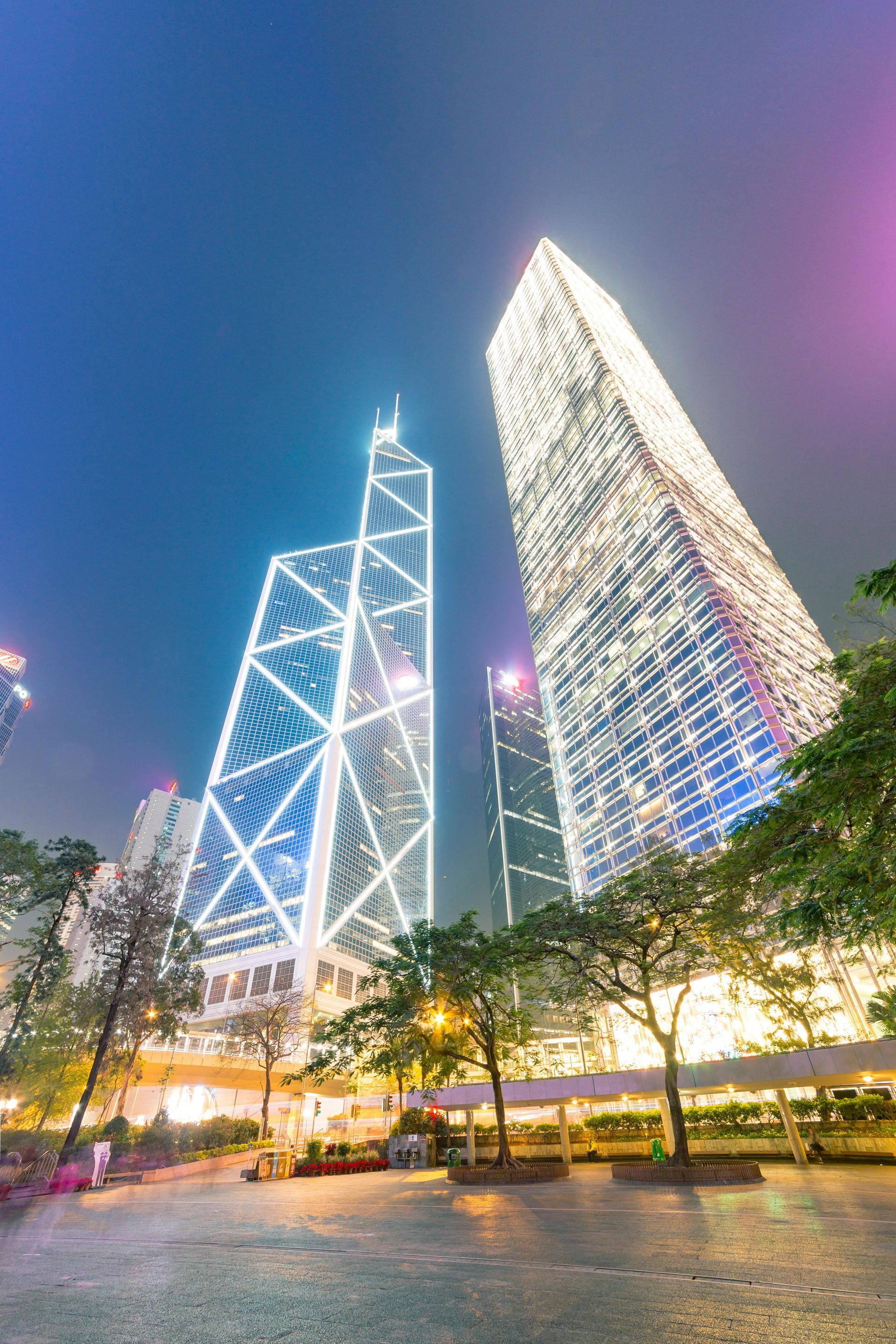 A group of tall buildings are lit up at night in a city.