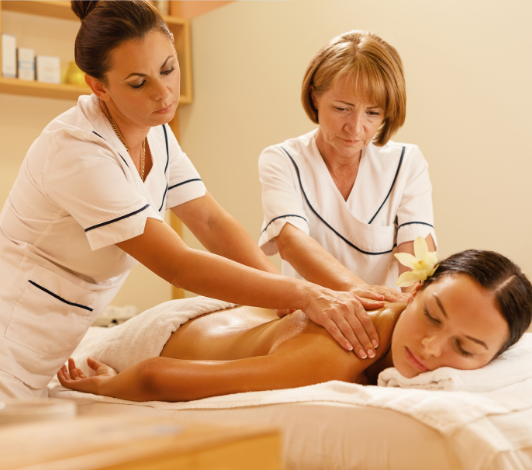Hands performing a massage on a back, with red light illuminating the area.