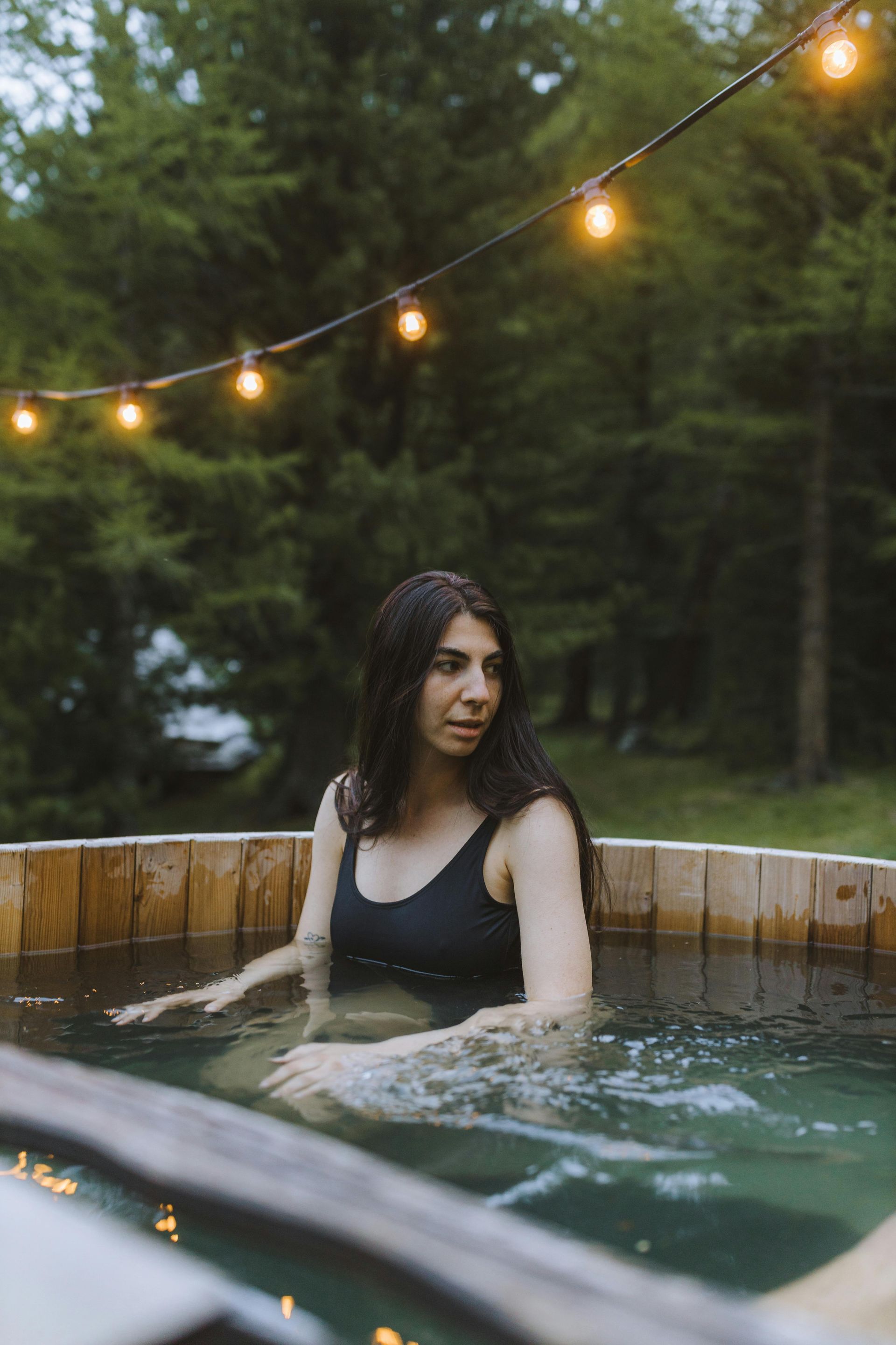 A bubbling hot tub in a spa setting with candles, greenery, and natural light.