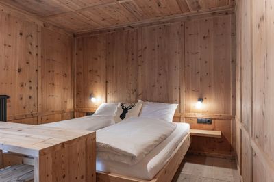 Ein Schlafzimmer mit Holzwänden und einem Bett mit weißen Laken.