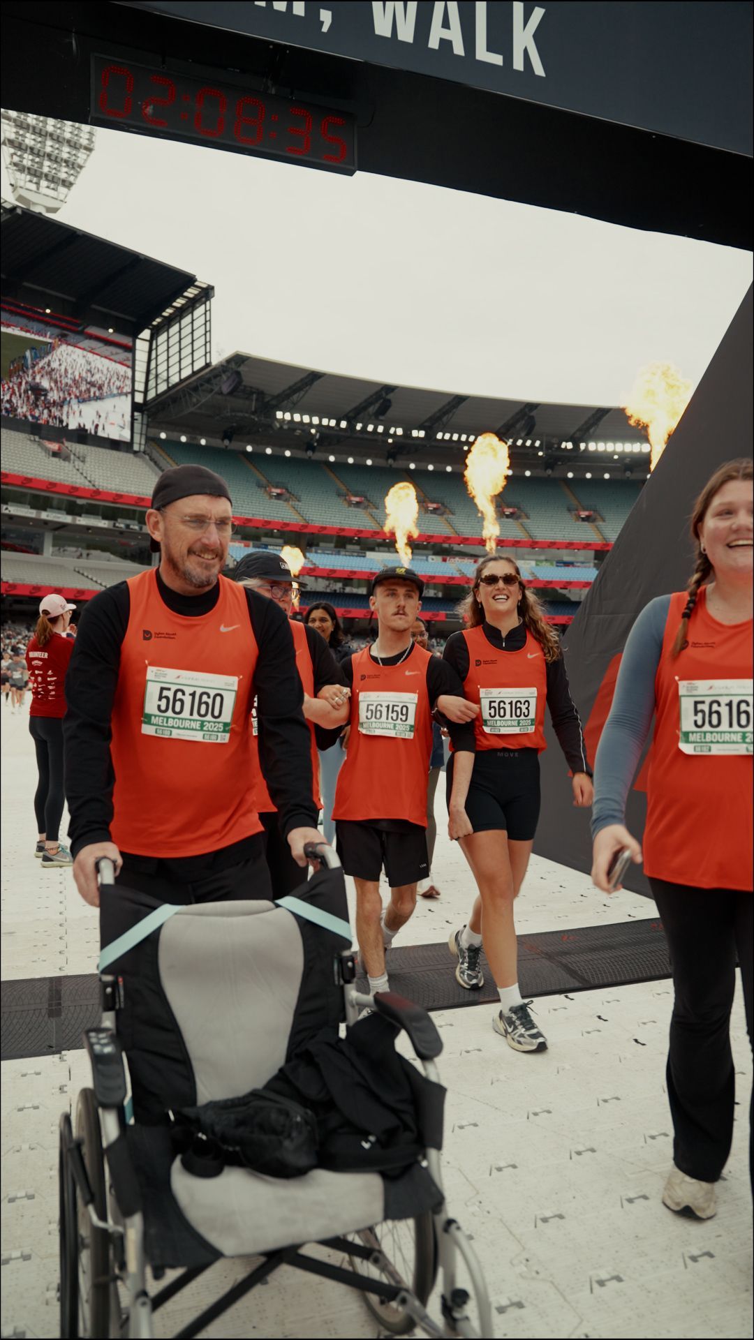 Recipient Cooper and family crossing the finish line with banner above.