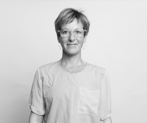 Black and white studio photo of board member Emily. She wears glasses.