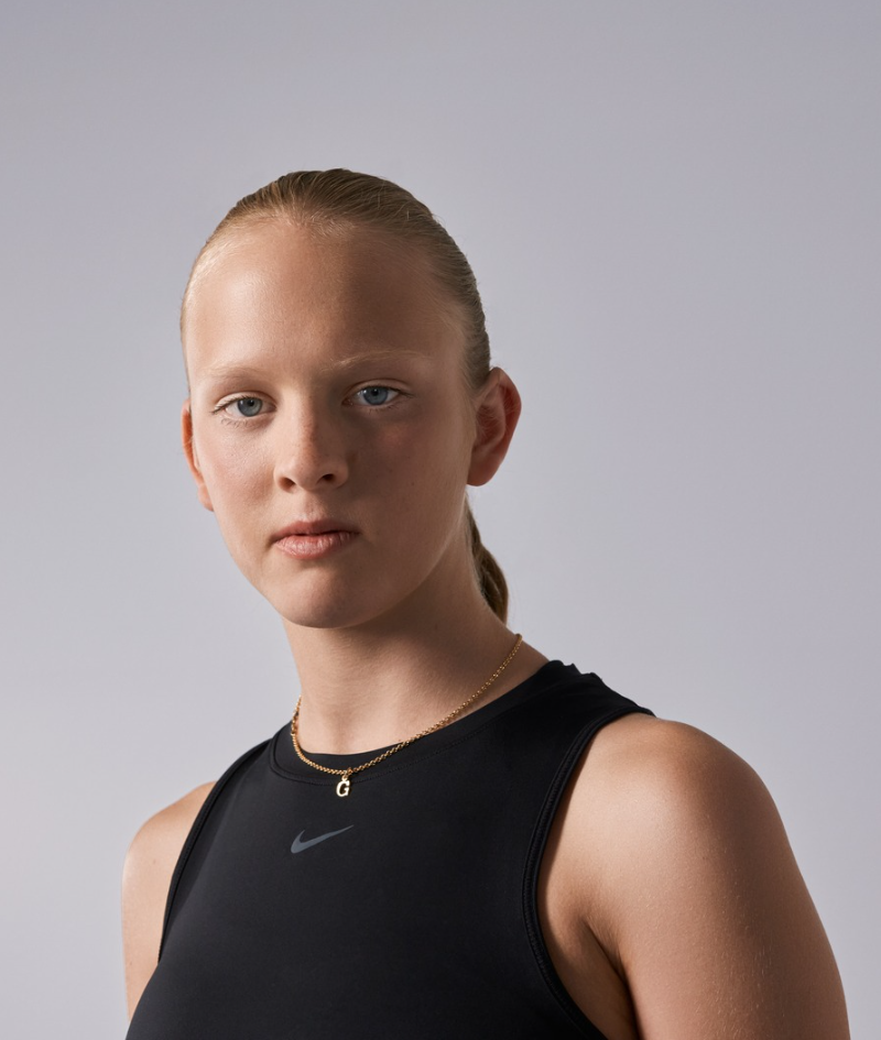 Close up side profile studio portrait of Grace who wears a black Nike running singlet.