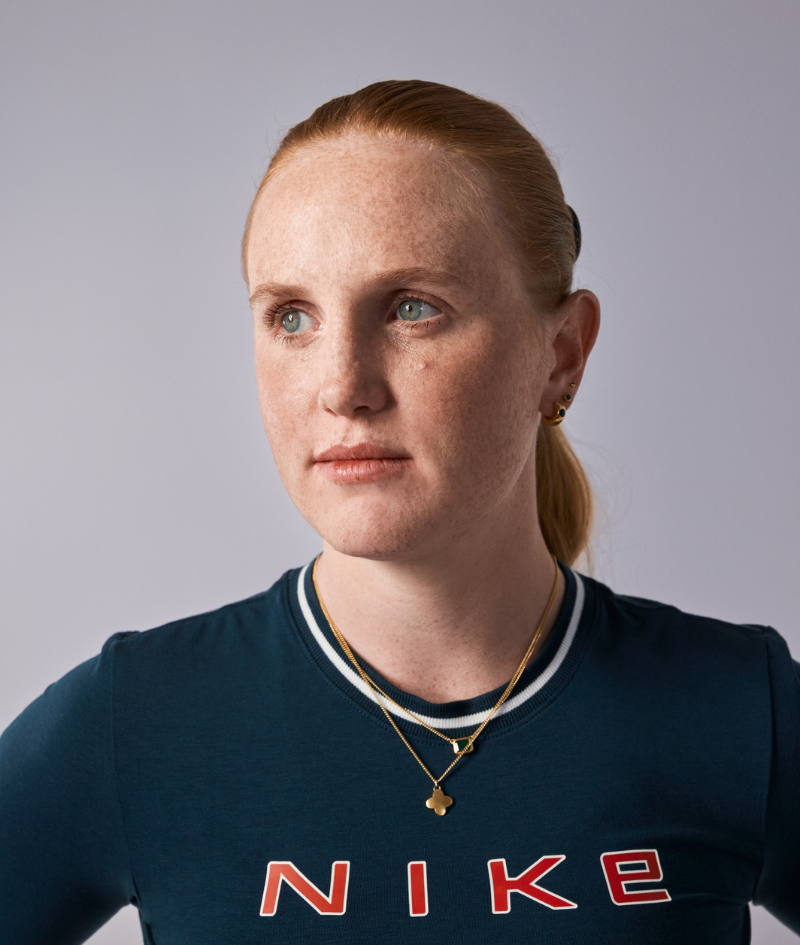 Close up studio portrait of Maggie who wears a green Nike long sleeve top.
