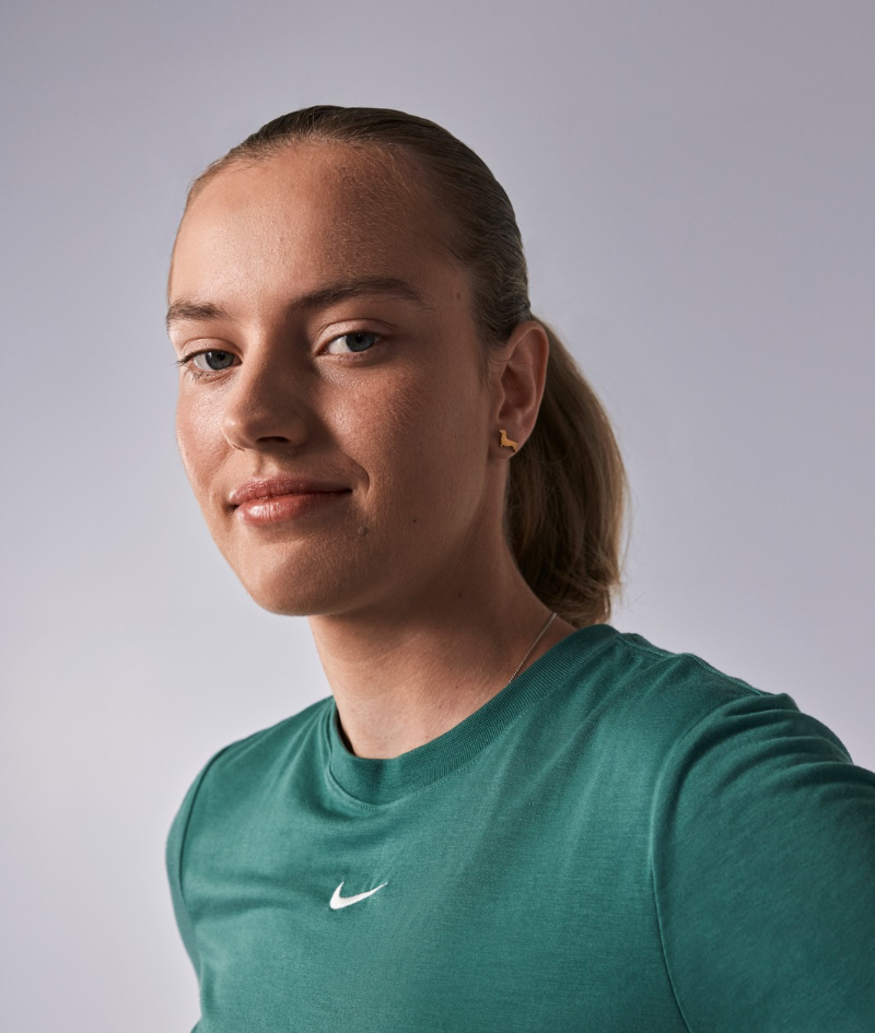 Close up side profile studio portrait of Mali who wears a green Nike branded t-shirt.