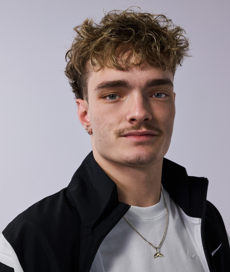 Close up side profile studio portrait of Eithen. He wears white t-shirt and black Nike spray.