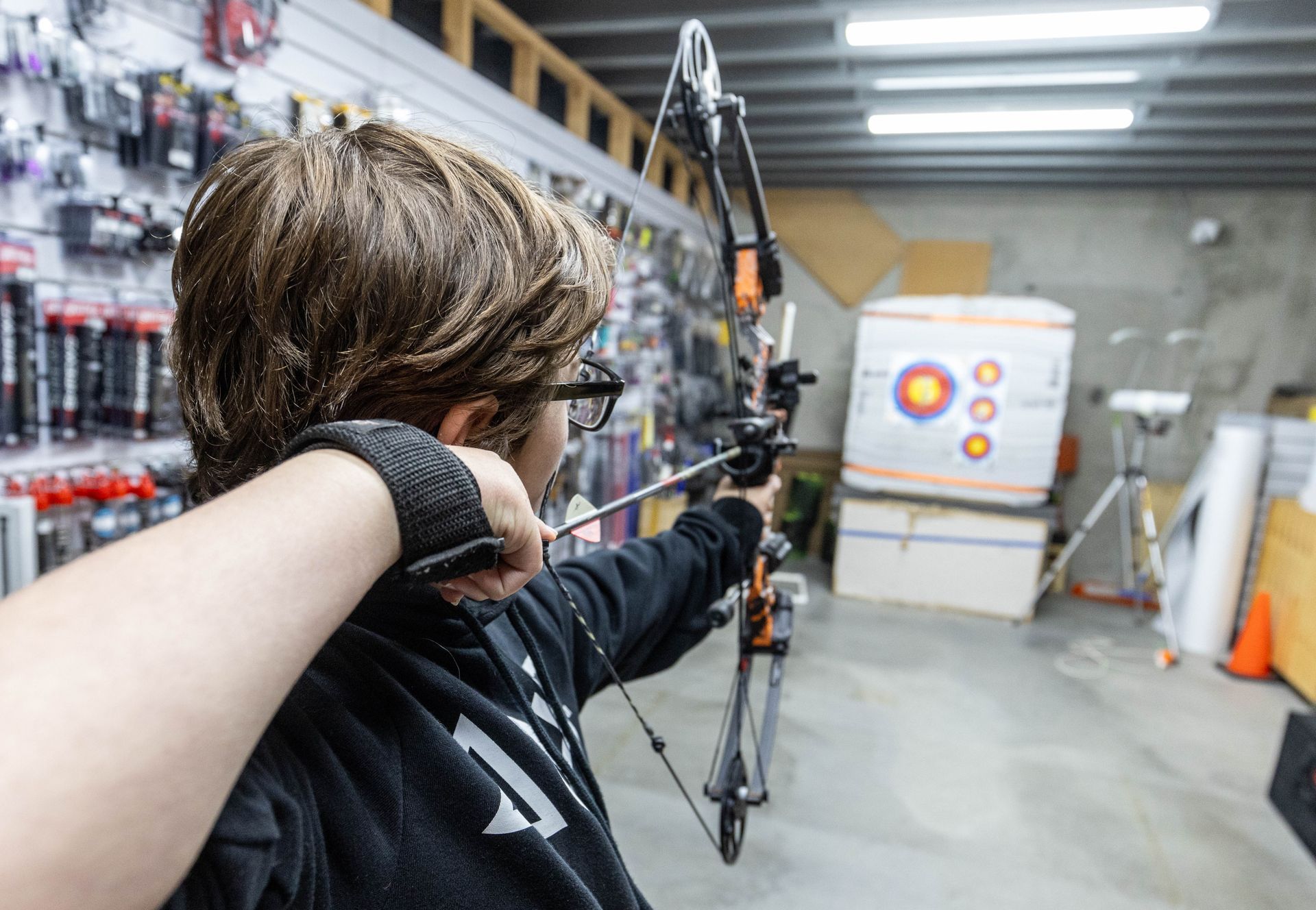 Behind shot of Josh aiming for an archery target with his bow and arrow.
