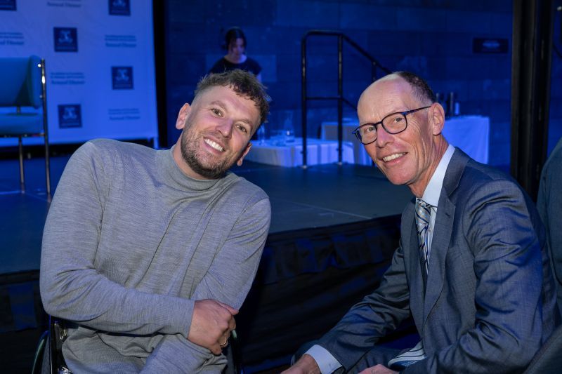 Close up shot of Dylan (left) and Professor Paul Kofman (right) seated whilst posing for a photo.