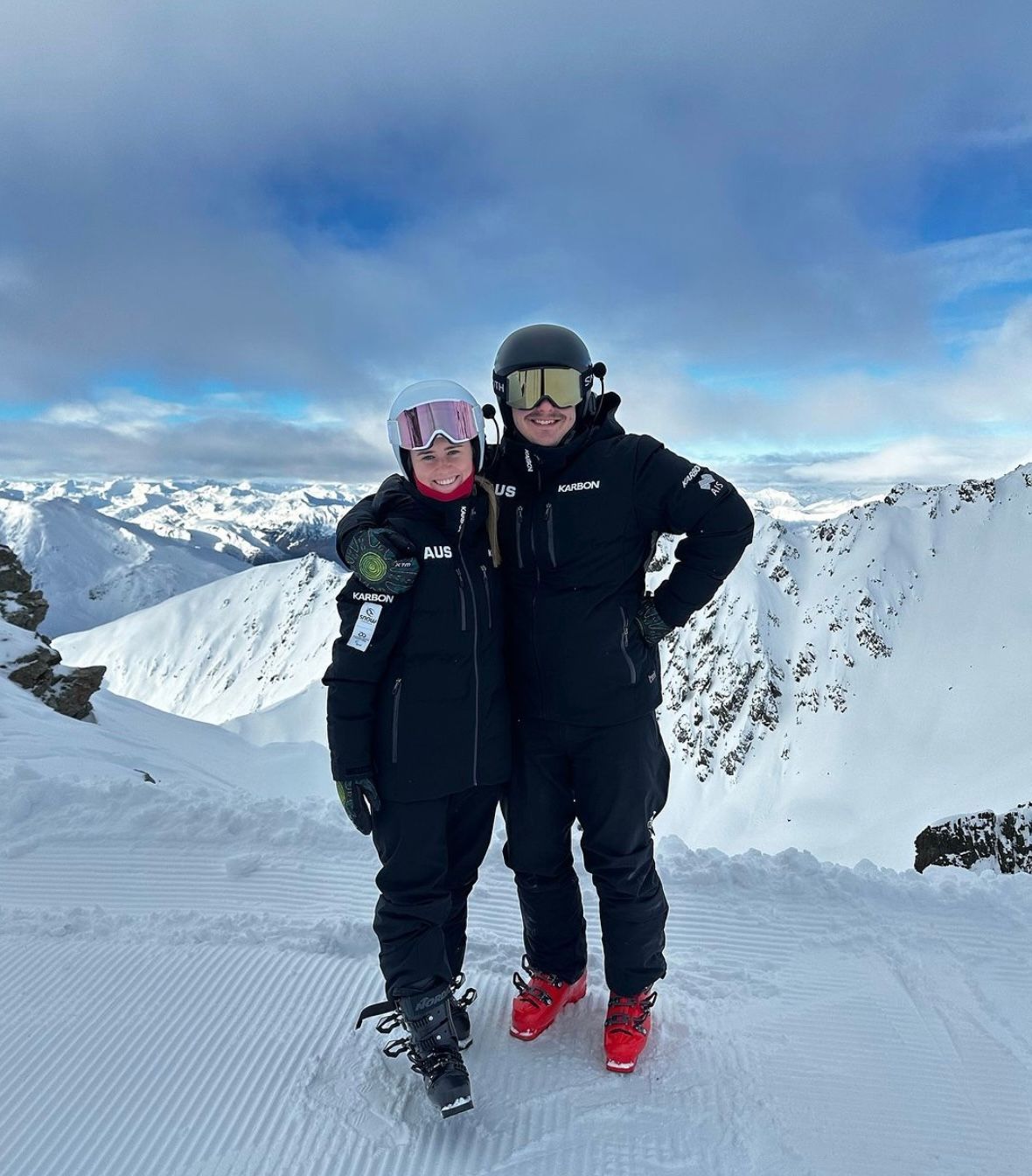 Recipient Georgia (left) and guide (right) smiling to camera decked in snow gear. Snow mountains are in the background.