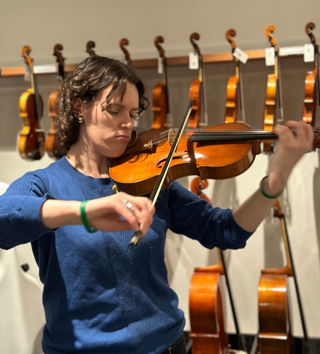 Recipient Sophia, playing the viola with multiple hanging violas in the background.