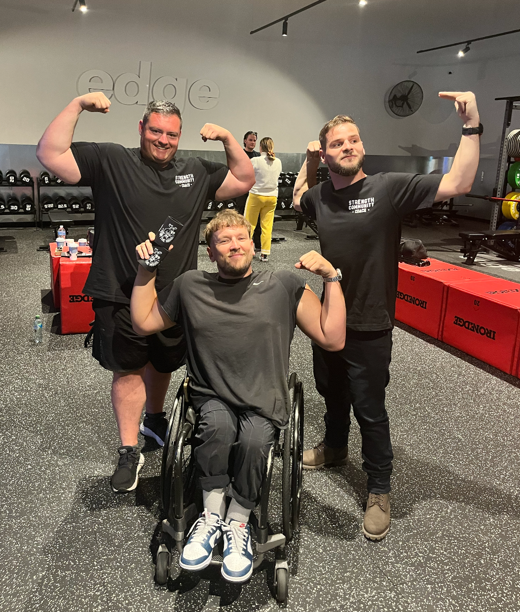 Pictured inside an Iron Edge gym, Dylan middle and with recipient Connor (right) and coach (left). All three are flexing their arms.