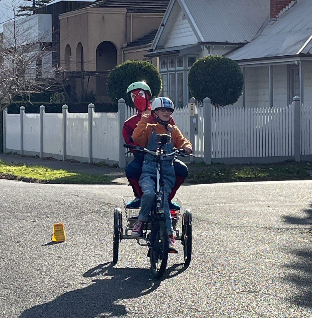 Recipient Sam, dinking friend in a spider man kit on a tricycle.