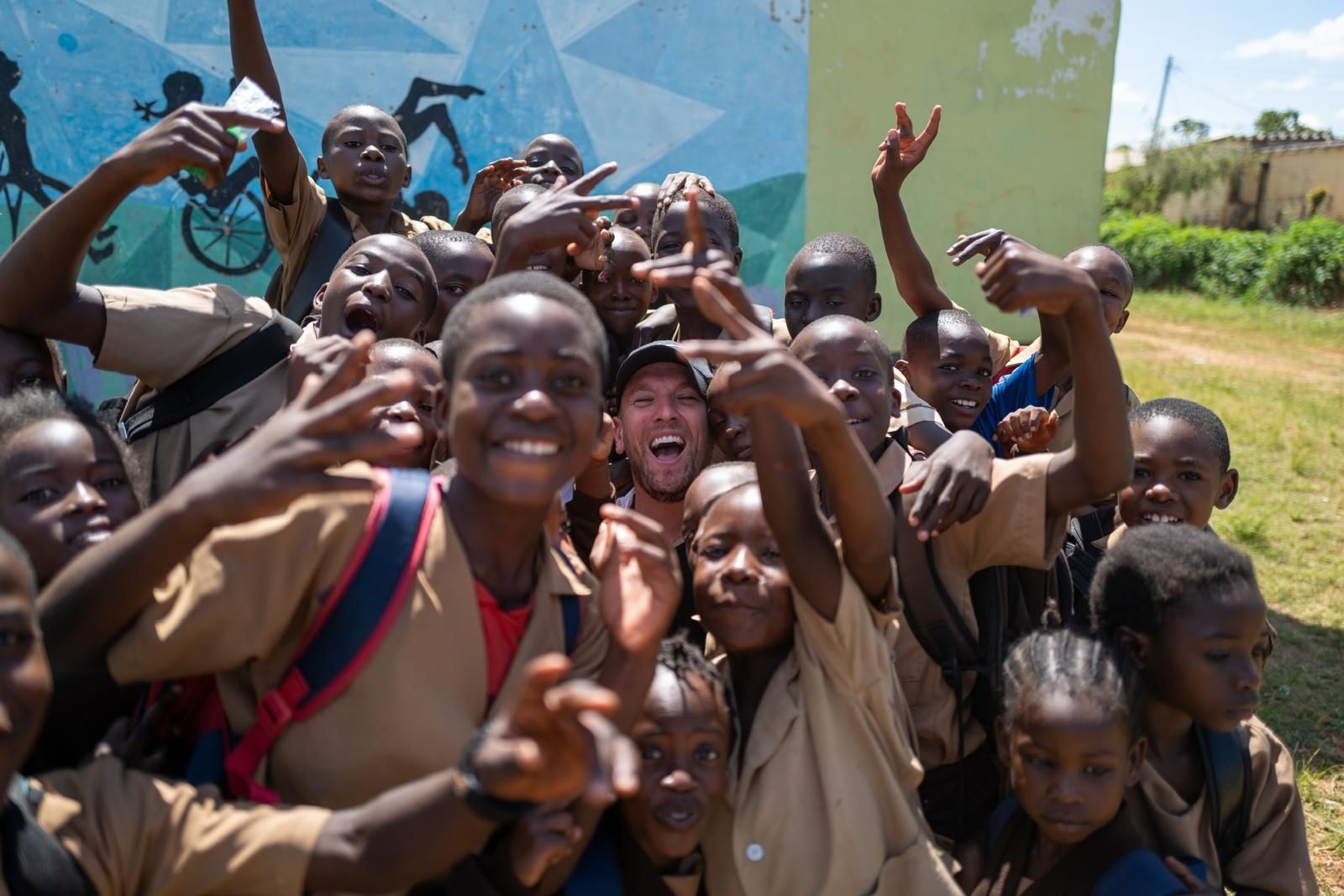 Dylan surrounded by a large group of school kids all smiling to the camera. Dylan's head can just be