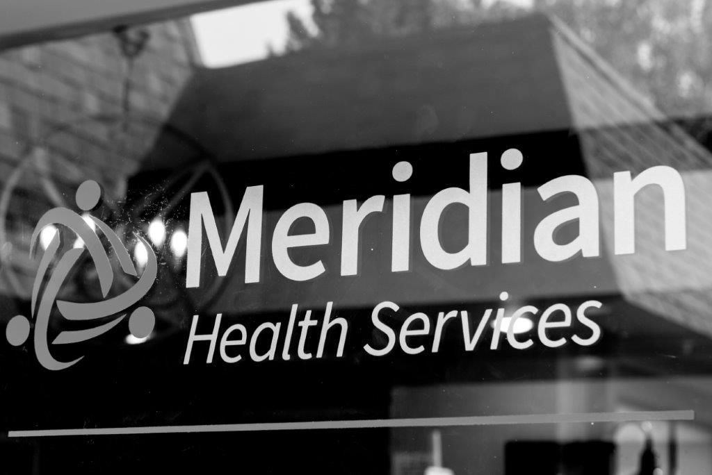 Meridian Health Services logo on a glass door.