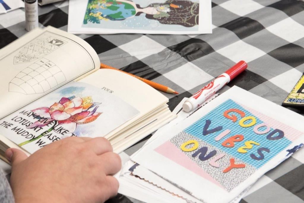 Person coloring in an open book with a floral drawing, and a 