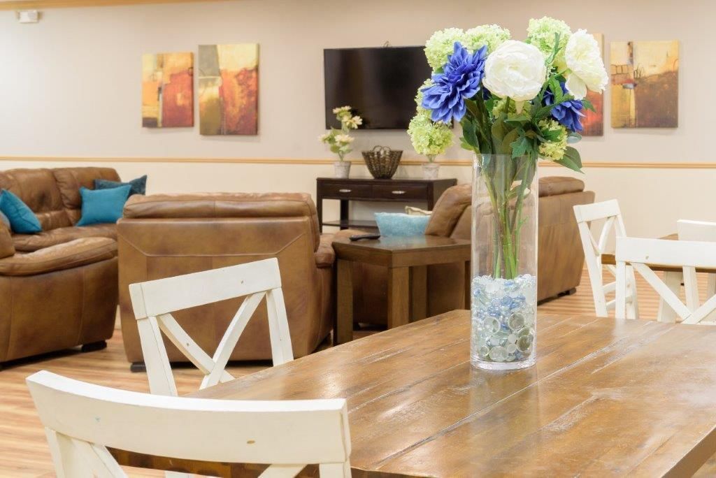 Living room with brown leather couches, TV, table, and vase of flowers.