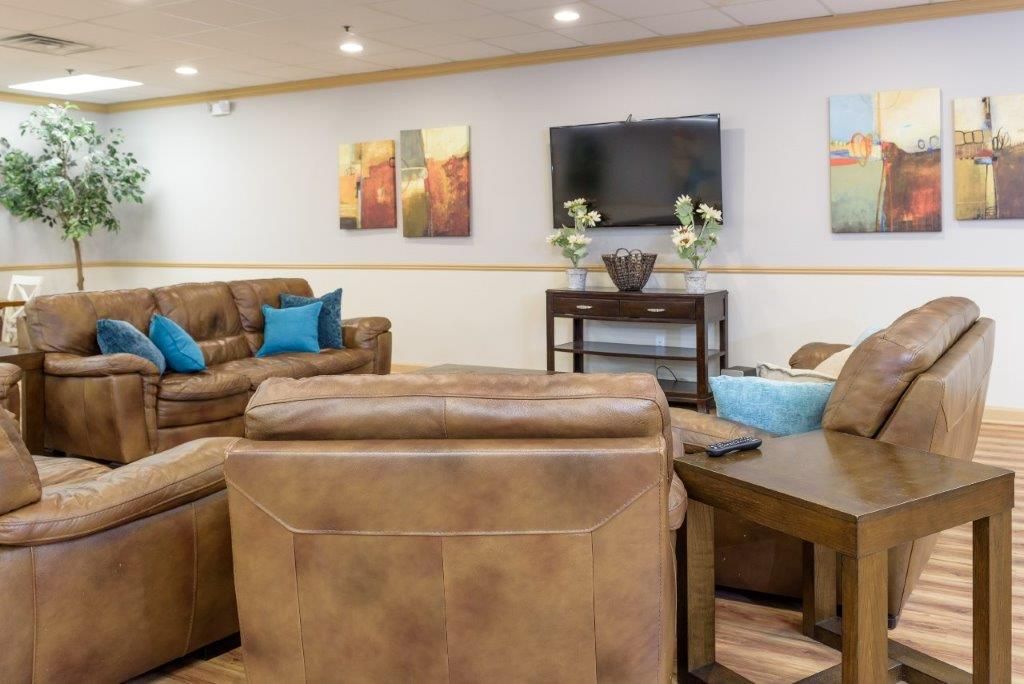 Spacious living room with leather sofas, artwork, a TV, and a side table.