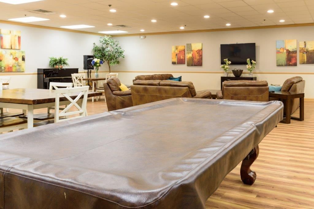 Game room with covered pool table, seating area, TV, and artwork.