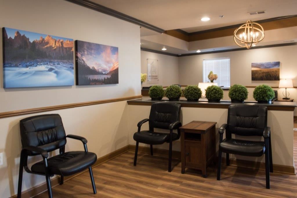 Waiting room with art, black chairs, and wooden flooring.