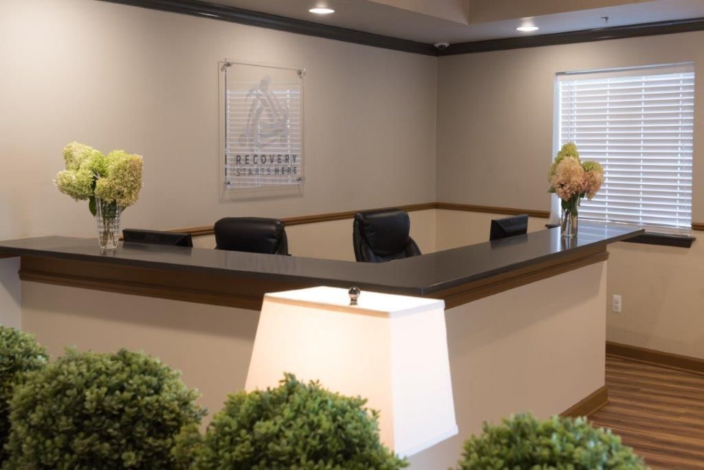 Reception desk with flowers and a logo. Dark counter and brown trim.
