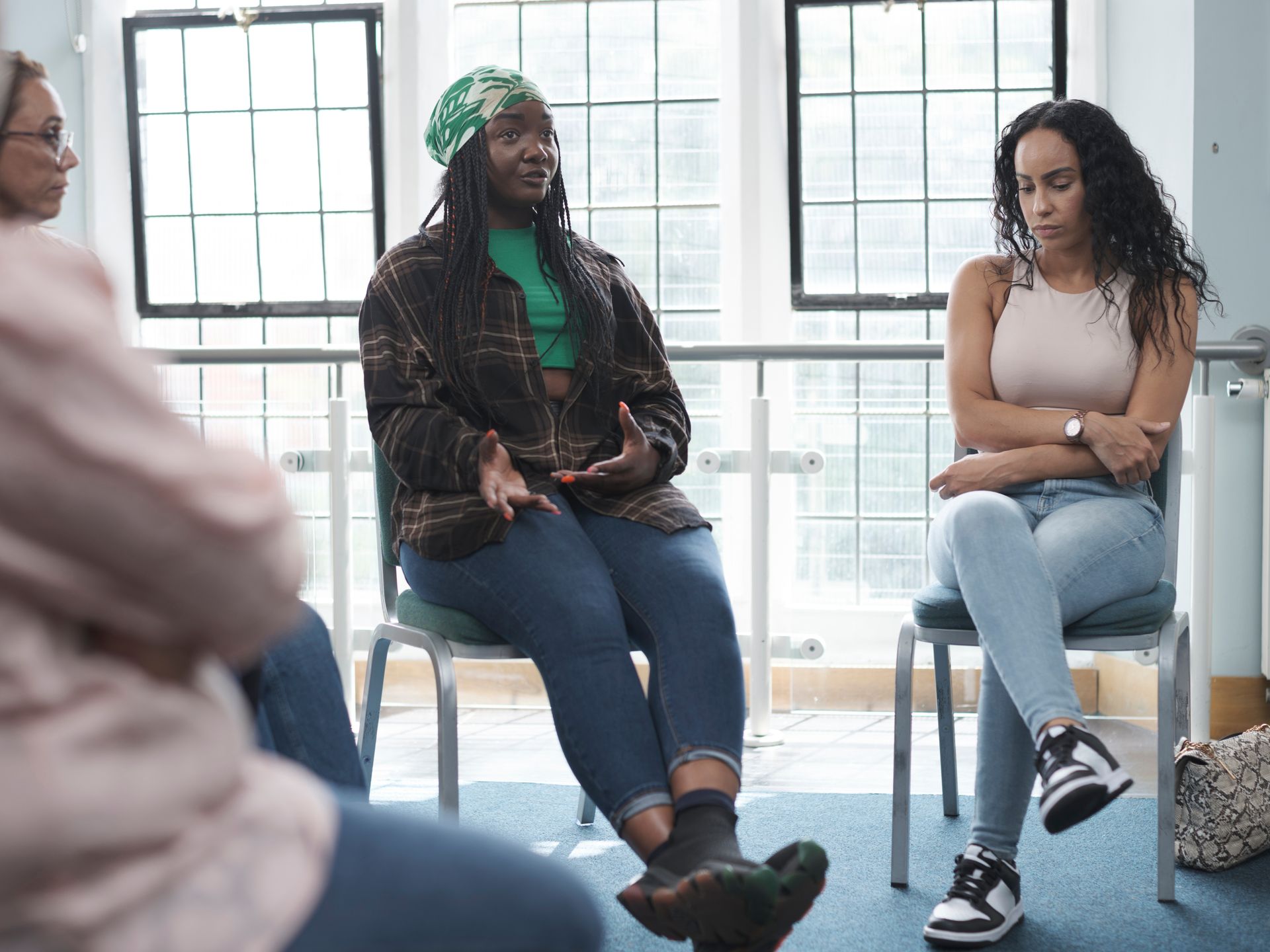 Three people sit in a bright room, talking in a small group circle.