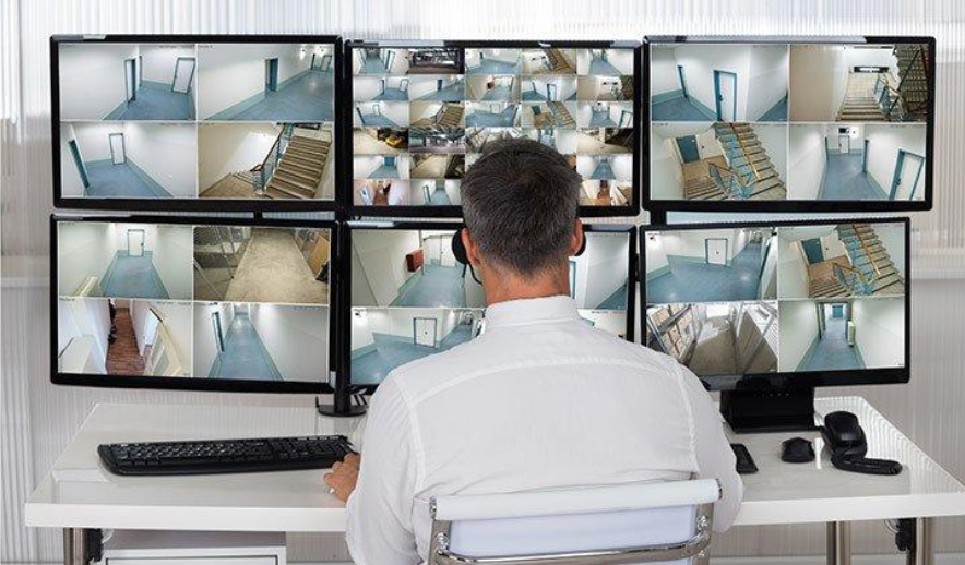 A man is sitting at a desk looking at a bunch of monitors.