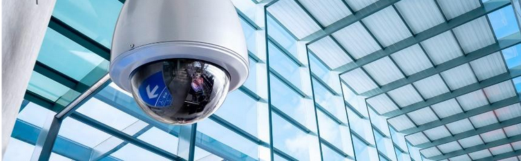 A security camera is hanging from the ceiling of a building.