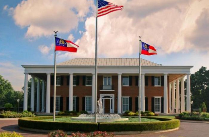 Three flags are flying in front of a large building
