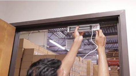 A man is installing a door lock in a warehouse.